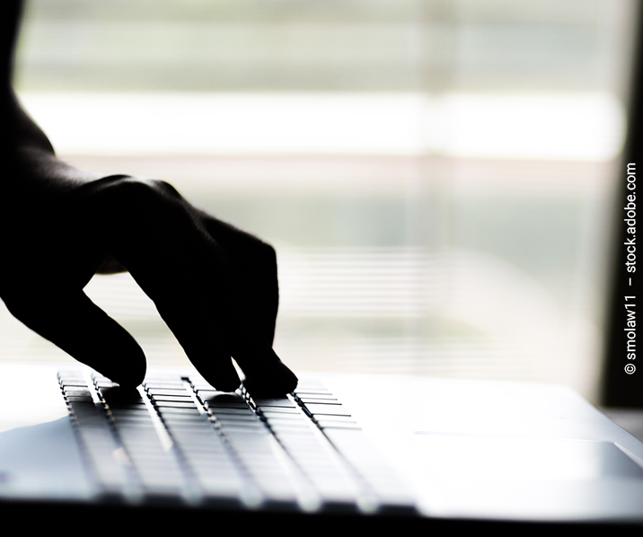 Finger tippen auf der Tastatur eines Laptops.