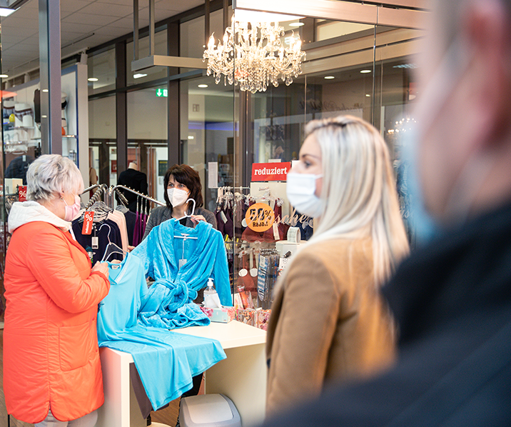 Menschen mit Mund-Nasen-Schutz in einem Kleidungsgeschäft