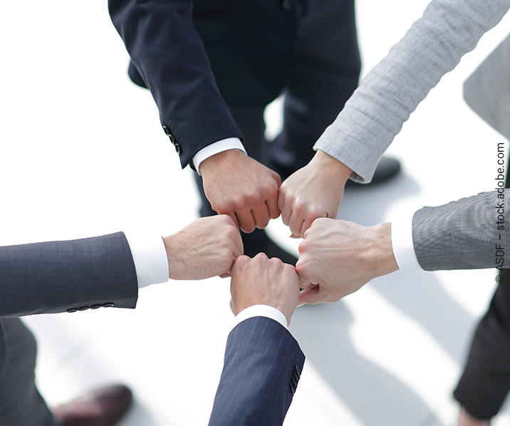 Fäuste von Teammitgliedern werden zusammengehalten.