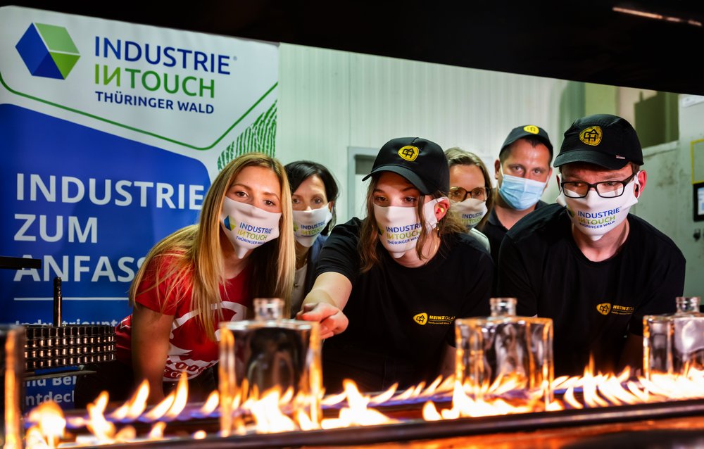 Eine Gruppe mit Mund-Nasen-Schutz betrachtet das Herstellung von Glasflacons