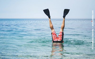 Mann macht einen Kopfstand im Meer